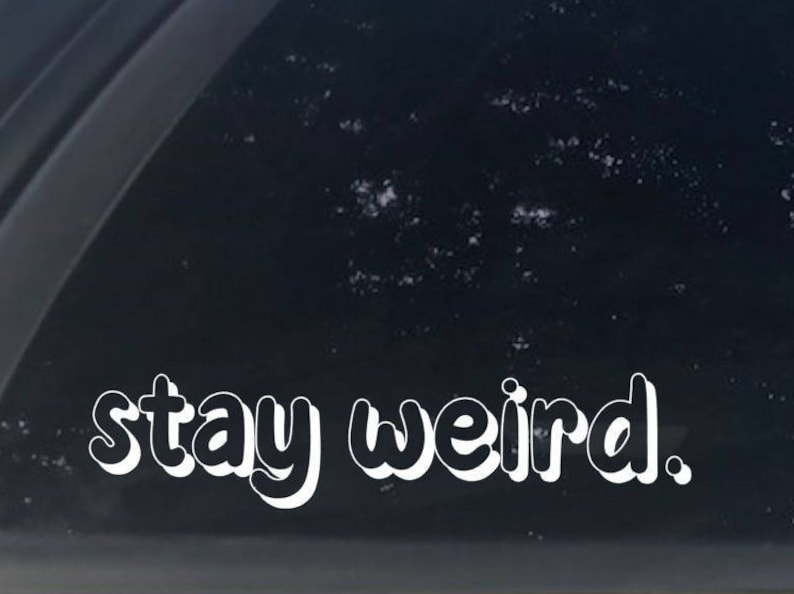 K&ouml;nnte beinhalten: Wei&szlig;er Vinyl-Aufkleber mit dem Text "stay weird". Der Text ist in einer Blasenschrift.
