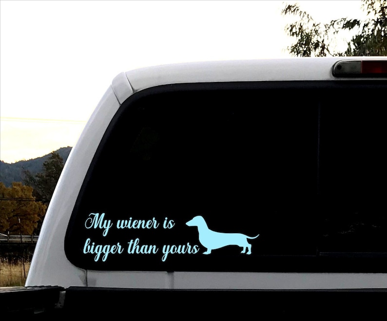 May include: A white truck with a black window decal that says "My wiener is bigger than yours" and a light blue silhouette of a dachshund.