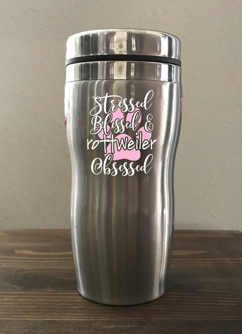May include: Stainless steel travel mug with a white design that says "Stressed Blessed & Rottweiler Obsessed" with a pink paw print.