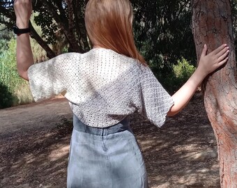 May include: A white crocheted shrug with a light blue and white ombre design. The shrug is worn over a blue dress.