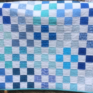 Couette pour bébé faite main en neuf pièces dans des tons de bleu.