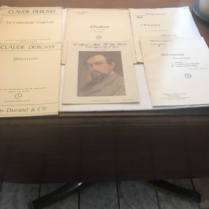 May include: A collection of five vintage sheet music books by Claude Debussy. The books are titled "La Cathédrale Engloutie", "Minstrels", "Ondine", "Images", and "Estampes".