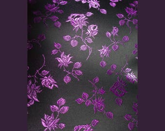 May include: Purple floral pattern on a black fabric background. The fabric has a subtle sheen and a textured surface.