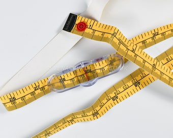 May include: A yellow measuring tape with black markings and a clear plastic measuring tool with a red button. The tape reads "Facechstonese Germany" and has numbers in inches and centimeters.