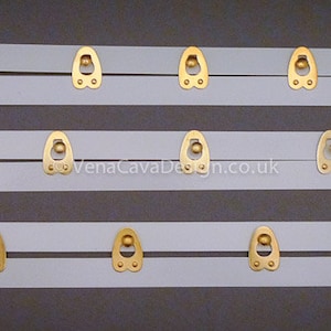 May include: Three white plastic bra strap extenders with gold metal hooks and eyes. The extenders are in different lengths.