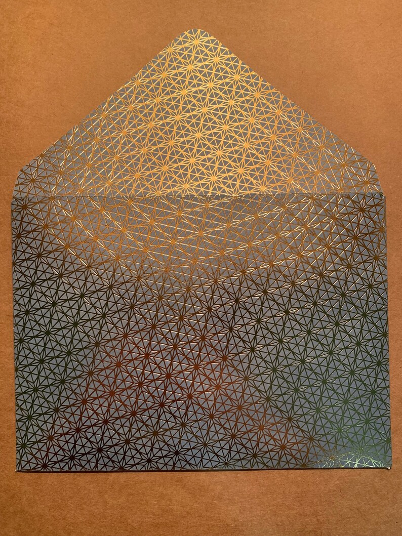May include: A gray envelope with a gold geometric pattern. The pattern is a repeating design of stars and triangles.