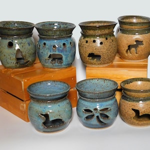 May include: A collection of eight ceramic oil diffusers with various animal cutouts. The diffusers are in shades of brown, blue, and green with a speckled glaze.