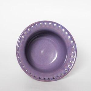 Puede incluir: Un peque&ntilde;o cuenco de cer&aacute;mica morado con un borde decorativo festoneado. El cuenco tiene un acabado liso y esmaltado y es perfecto para servir peque&ntilde;os aperitivos o postres.