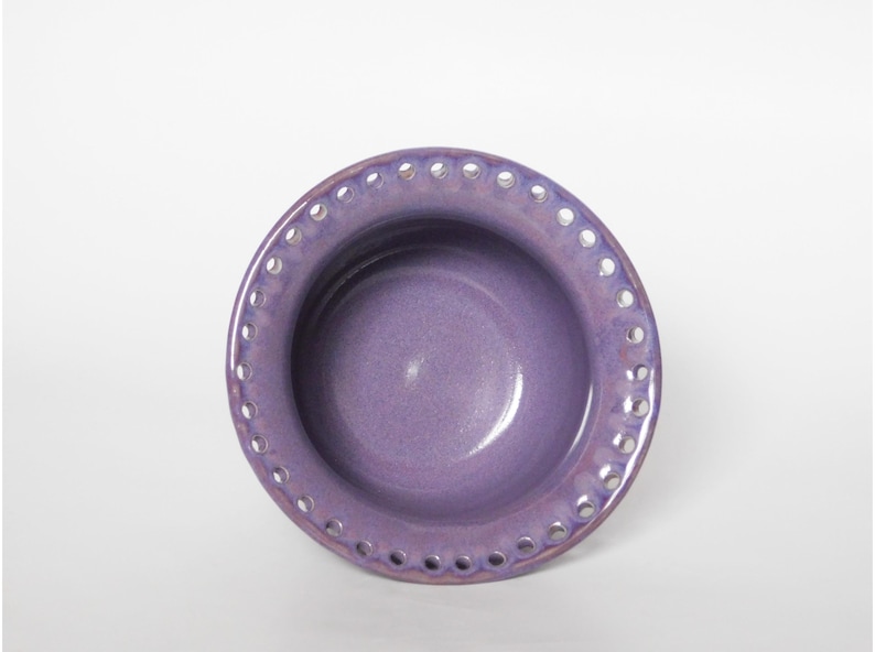 Puede incluir: Un peque&ntilde;o cuenco de cer&aacute;mica morado con un borde decorativo festoneado. El cuenco tiene un acabado liso y esmaltado y es perfecto para servir peque&ntilde;os aperitivos o postres.
