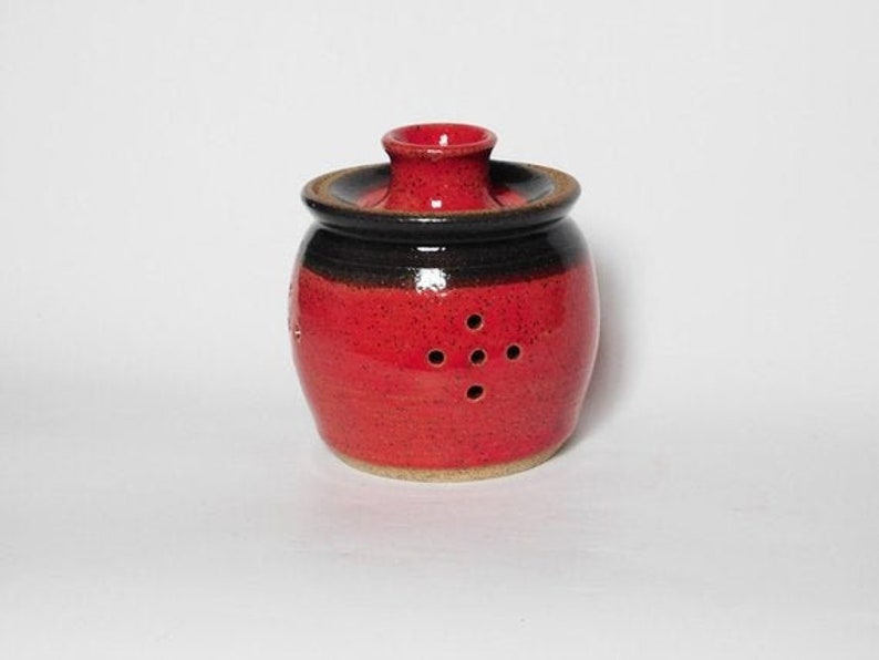 May include: Red ceramic garlic keeper with a black lid and holes for ventilation.