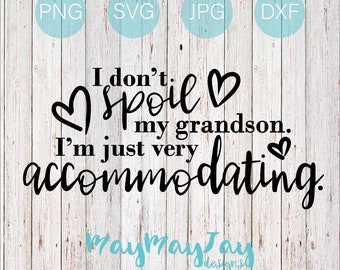 May include: Black and white text graphic on a wood background. The text reads "I don't spoil my grandson. I'm just very accommodating." with hearts around the words "spoil" and "accommodating". The text "raymaytay designs" is at the bottom of the graphic.