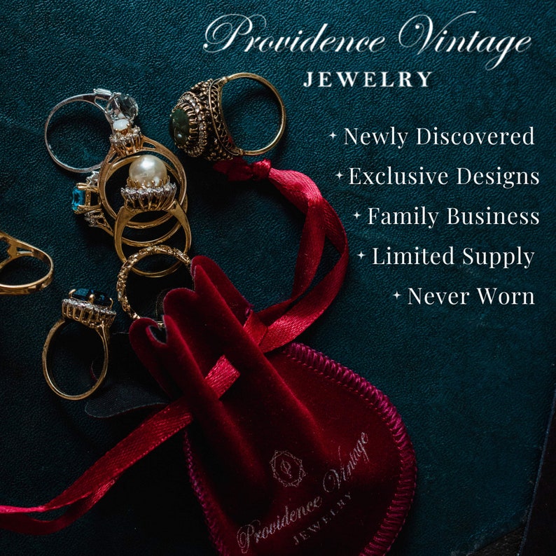May include: A red velvet pouch with the text "Providence Vintage Jewelry" on it, surrounded by a red ribbon and a collection of vintage rings with gold and silver settings, including a pearl ring and a ring with a blue gemstone.