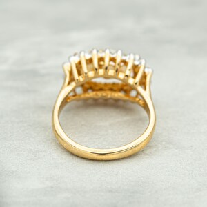 May include: A gold ring with a row of small white stones set in a delicate, intricate design.