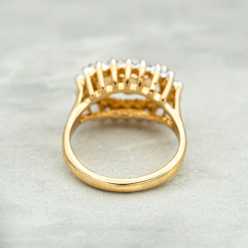 May include: A gold ring with a row of small white stones set in a delicate, intricate design.