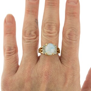 May include: A gold ring with a large oval opal gemstone surrounded by smaller clear gemstones.
