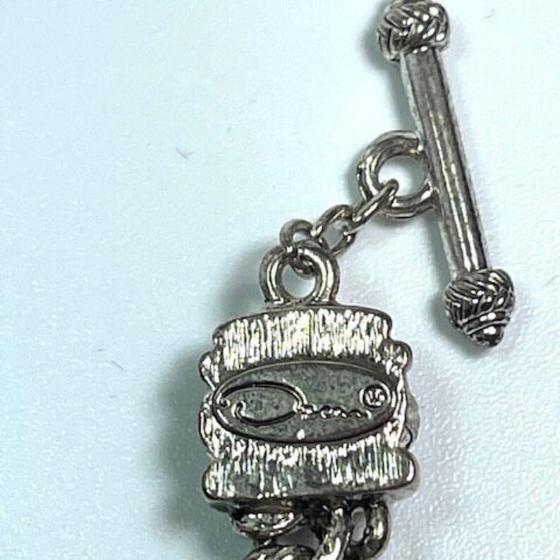 Puede incluir: Primer plano de un cierre de collar plateado con una barra de palanca. El cierre presenta el nombre de la marca "Oscar" en un dise&ntilde;o ovalado estilizado. La cadena es de estilo cuerda trenzada.