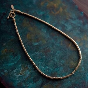May include: A gold chain necklace with a box clasp. The chain is made of small, interlocking links.