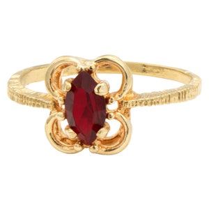 May include: A gold ring with a red marquise-shaped gemstone set in a floral design.
