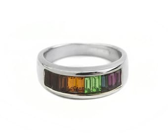 May include: A silver band ring with a row of colorful gemstones. The gemstones are arranged in a rainbow pattern, with brown, orange, green, blue, and purple stones.