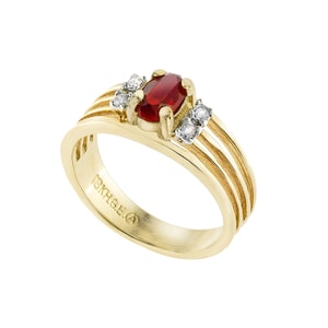 May include: A gold ring with a red oval gemstone and three smaller clear gemstones. The ring has a textured band with three grooves. The inside of the band is marked "10K H.G.E."