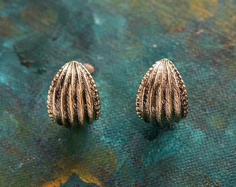May include: A pair of gold-toned earrings shaped like seashells with a ribbed texture.