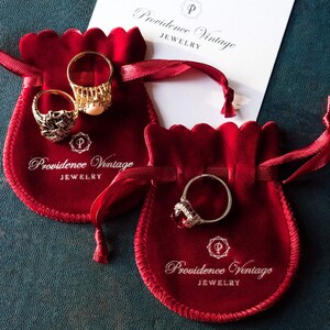 May include: Two red velvet jewelry pouches with gold and silver rings inside. The pouches have the text "Providence Vintage Jewelry" printed on them.