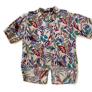 May include: A short-sleeved button-up shirt with a beige background and an abstract print in shades of red, purple, green, and blue.