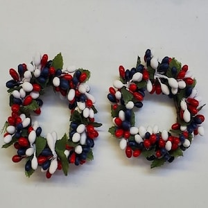 May include: Two small wreaths made of red, white, and blue berries. The wreaths are perfect for adding a festive touch to any occasion.