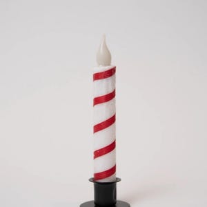 Puede incluir: Una vela a rayas blancas y rojas con una base negra. La vela tiene una luz en forma de llama en la parte superior. La vela es una decoración festiva.