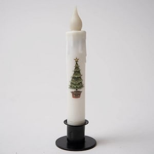 May include: A white LED Christmas candle with a painted green Christmas tree design. The candle has a realistic flame shape and sits in a black metal holder. A gold star is at the top of the tree.