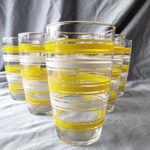 May include: Set of six clear glass drinking glasses with yellow and white striped designs.