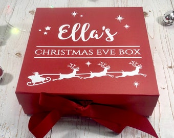 May include: Red Christmas Eve box with a white ribbon and the text "Ella's Christmas Eve Box" and a white silhouette of Santa Claus in a sleigh pulled by reindeer.