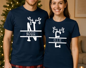May include: Two people wearing matching navy blue t-shirts with a white reindeer design and names. The shirt on the left says "Noah" and the shirt on the right says "Ellie". They are also wearing red and black plaid pajama bottoms.