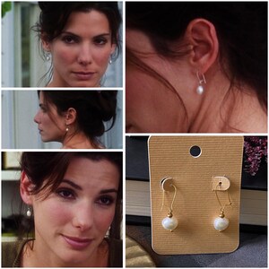 May include: A pair of gold earrings with white pearl drops on a brown card. The earrings are on a white background.