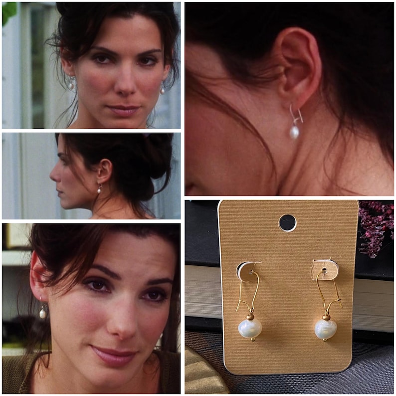 May include: A pair of gold earrings with white pearl drops on a brown card. The earrings are on a white background.