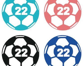 May include: Four soccer balls with a heart shape containing the number 22. The soccer balls are in the colors blue, pink, black, and blue.