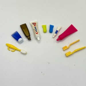 May include: A collection of miniature toiletries, including toothpaste, toothbrushes, and hand soap, in a variety of colors, including blue, pink, yellow, and white.
