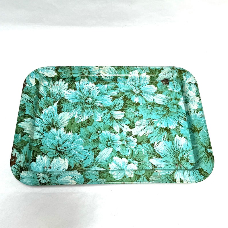 Puede incluir: Una bandeja de servir de metal vintage con un patr&oacute;n floral en tonos verdes y azules. La bandeja presenta un dise&ntilde;o repetitivo de flores estilizadas.