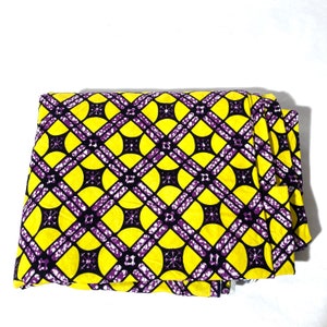 May include: Yellow fabric with a purple and black geometric pattern. The pattern features circles and intersecting lines.