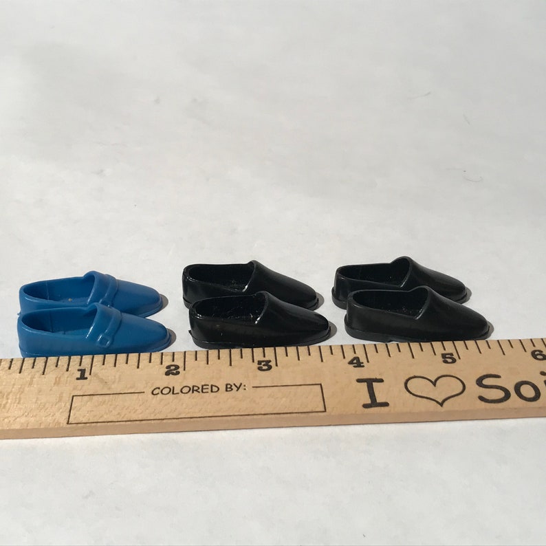 May include: Two pairs of doll shoes. One pair is blue and the other pair is black.
