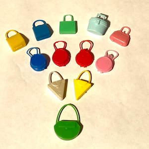 May include: A collection of ten miniature purses and bags in various colors, including blue, green, yellow, red, and pink. The purses are made of plastic and have a variety of styles, including a bucket bag, a satchel, and a crossbody bag.
