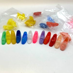 May include: A collection of 14 miniature plastic shoes in various colors, including yellow, blue, pink, red, and white. The shoes are arranged in two rows on a white surface.