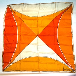 May include: Square silk scarf with a geometric design in shades of orange, yellow, and white. The scarf features curved and angular shapes, with a signature in the bottom right corner. The scarf is a vintage accessory.