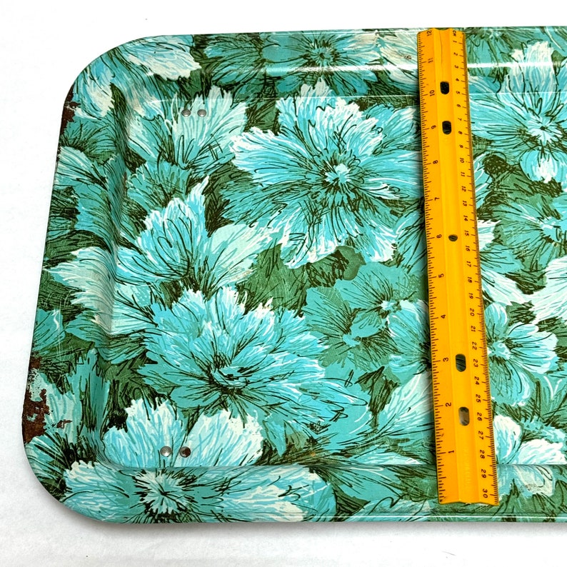 Puede incluir: Una bandeja de servir vintage de metal con un dise&ntilde;o floral en tonos azules y verdes. La bandeja tiene un aspecto ligeramente desgastado y mide aproximadamente 30 cm por 46 cm.