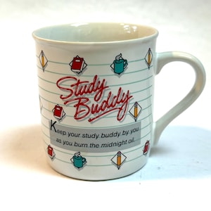 May include: White ceramic mug with a blue and green design. The mug has the words "Study Buddy" in red and the text "Keep your study buddy by you as you burn the midnight oil."