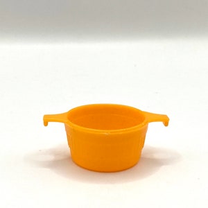 May include: A small, bright orange plastic colander with two handles. The colander is designed for straining small amounts of food.