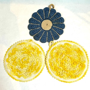 May include: Three crocheted pot holders. One is blue with a flower design, and the other two are yellow with a swirl design.