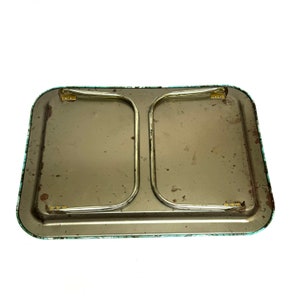 Puede incluir: La parte inferior de una bandeja de metal vintage con un patr&oacute;n floral verde y blanco. La bandeja tiene dos patas de metal que se pliegan para su almacenamiento.
