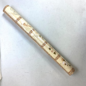 May include: A roll of beige wallpaper with a floral pattern. The pattern features small brown and white flowers and leaves. The wallpaper is wrapped in plastic.