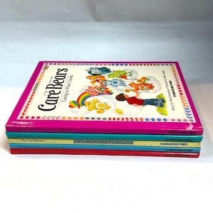 May include: A stack of Care Bears children's books. The top book is titled "Caring is What Counts" with a pink cover featuring Care Bears characters and a rainbow. Other books in the stack have blue, green, and red covers.